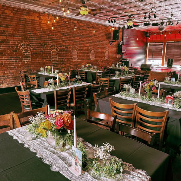 Recess Southern Gastro Pub's dining area with tables set for an event, featuring brick walls and a stage.