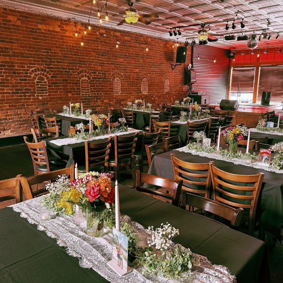 Recess Southern Gastro Pub's dining area with tables set for an event, featuring brick walls and a stage.