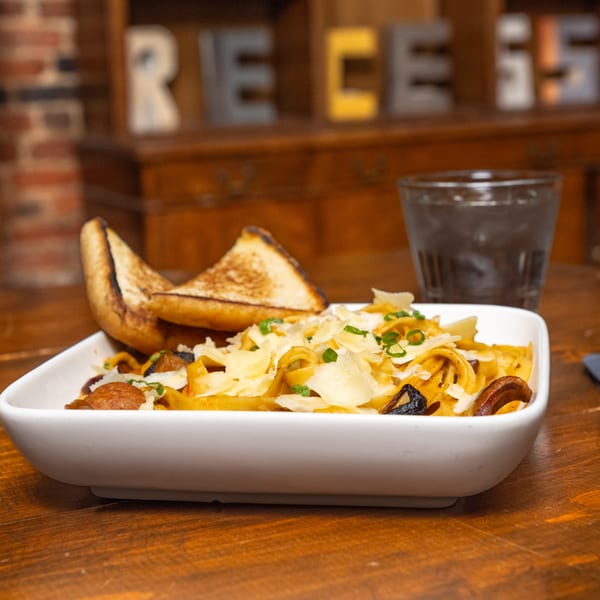 Recess Southern Gastro Pub's pasta dish with mushrooms, cheese, and toast on a wooden table.