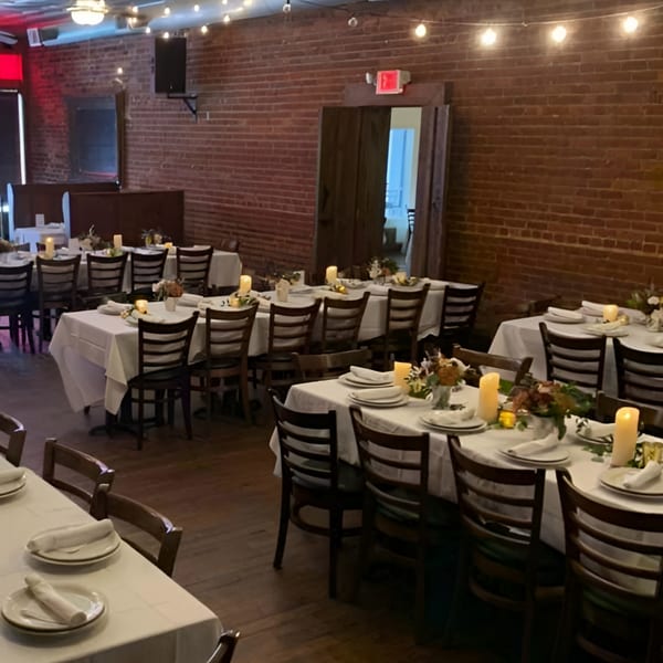 Recess Southern Gastro Pub's dining room with tables set with white tablecloths, candles, and floral centerpieces.