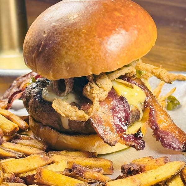 A Southern Gastro Pub burger with bacon, cheese, and crispy fried onions, served with fries.